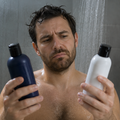 Hombre en la ducha dudando qué champú usar antes de un injerto capilar